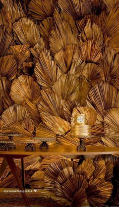 a wooden table sitting in front of a wall covered with lots of fan like material