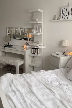 a bedroom with a white bed, desk and mirror on the wall next to it