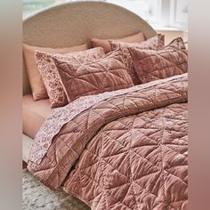 a bed with pink comforter and pillows on it