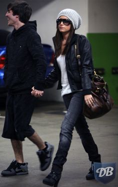 a man and woman walking down the street holding hands