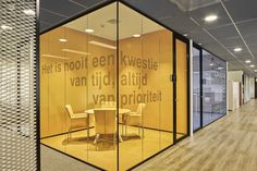 an office with glass walls and chairs in the center, surrounded by wood flooring