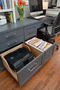 an open drawer in the middle of a desk with a computer and printer on it