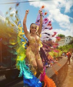 a woman in a colorful costume is dancing on the side of a road while people watch