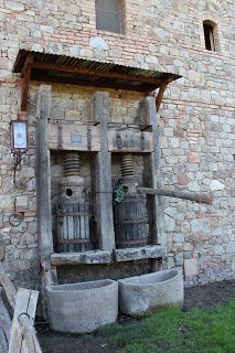 an old water fountain in front of a brick building with two buckets on the ground