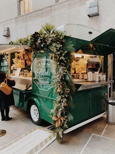 a green food truck parked in front of a building