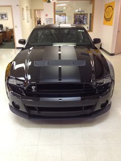 the front end of a black mustang in a showroom