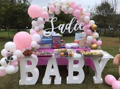 a baby shower is set up in the grass with pink and white balloons on it