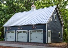 a blue garage with three doors and two lights on the roof, surrounded by trees