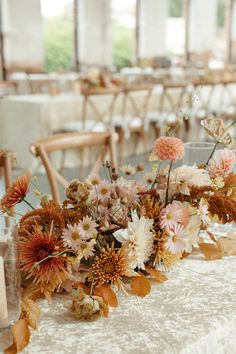 an arrangement of flowers on a table in a room with chairs and tables set up