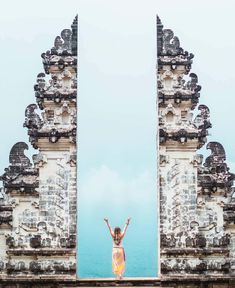 a woman standing in front of an archway with her arms up to the sky above her head