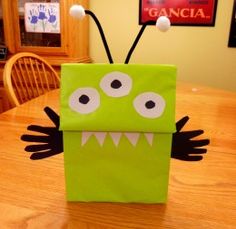 a green paper bag with eyes and mouth on it sitting on a table in front of a dining room