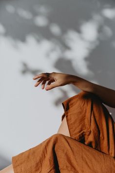 a person sitting on the ground with their hand extended up in front of her face