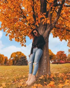 a woman leaning against a tree in the fall