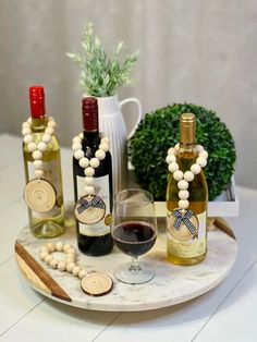 three bottles of wine are sitting on a marble tray with wooden beads and corks