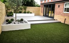 a modern garden with artificial grass and stone steps leading up to the decking area