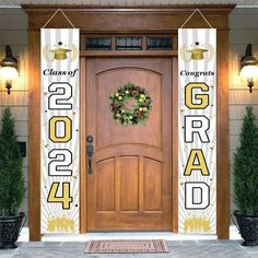 the front door of a building with two wreaths on each side and congratulations sign above it