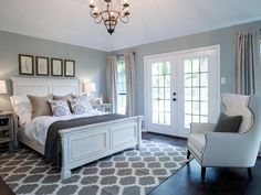 a bedroom with gray walls, white furniture and a chandelier hanging from the ceiling