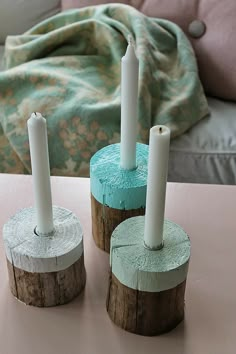 three candles sitting on top of wooden logs in the middle of a living room table