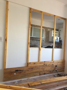 an unfinished room with wood framing in the foreground and a kitchen in the background