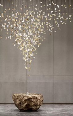 a large chandelier hanging from the ceiling over a stone bowl in front of a wall