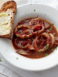 a white bowl filled with soup and bread on top of a cloth covered tablecloth