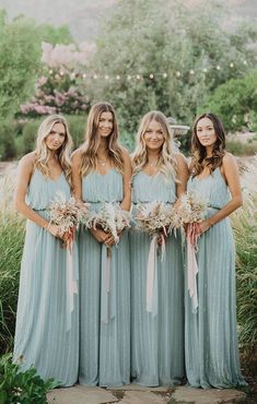 the bridesmaids are all dressed in blue dresses and holding bouquets with flowers