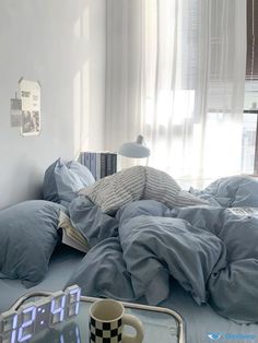 an alarm clock sitting on top of a bed next to a cup and tray with food