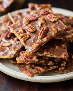 a white plate topped with pieces of chocolate covered pecan barkle bars on top of a wooden table