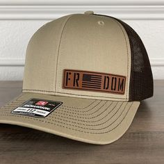 Freedom American Flag Patriotic Leather Patch Hat Khaki/Brown. Specifications: 🧢 Richardson original 112 trucker; adjustable for the perfect fit 🎩 60/40 cotton/polyester blend for comfort 📏 One size fits most 🏷️ Expertly laser engraved leatherette patch design 📦 Ships in 2 to 3 business days from our Orlando Studio Care Instructions: 🚫 Do not wash; spot clean only Please Note: 🌈 Colors may vary from photos based on your viewing screen. Brown Adjustable Hat With Curved Bill, Adjustable Brown Baseball Cap With Curved Bill, Brown Adjustable Curved Bill Hat, Brown Flat Brim Baseball Cap One Size, Urban Brown Snapback Baseball Cap, Brown Adjustable Cap, Casual Brown Trucker Hat With Flat Brim, Brown Flat Bill Baseball Cap For Outdoor, Brown Trucker Hat With Flat Brim