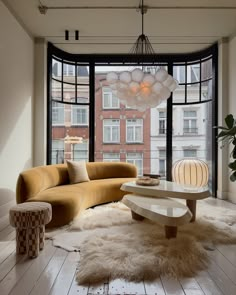 a living room filled with furniture next to a large window covered in lots of windows