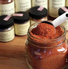 a jar filled with red chili seasoning sitting on top of a wooden table