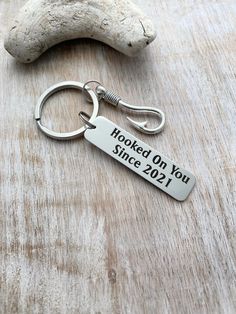 a metal keychain that says hooked on you since 2012 next to a bone