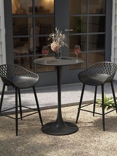 two chairs sitting at a table with wine glasses on it