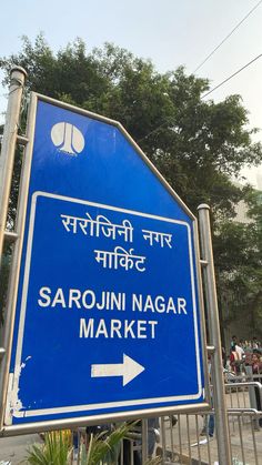 there is a blue sign that says sarojni nagar market and an arrow pointing to the right