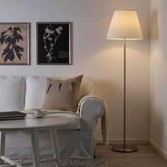 a white couch sitting next to a lamp on top of a table in a living room