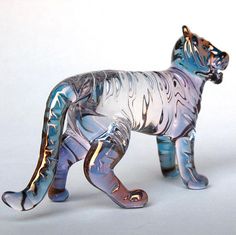 a glass figurine of a tiger on a white background with blue and silver stripes