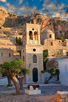 an old church in the middle of town with mountains in the backgrouds