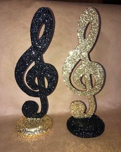 two black and gold glittered musical notes are standing next to each other on a table