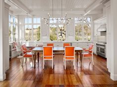 an open kitchen and dining room with hardwood flooring, white walls, and large windows