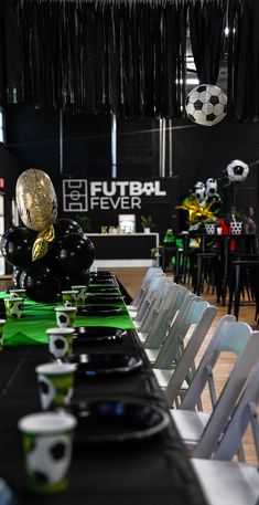 a long table with chairs and plates on it in a room filled with black tables