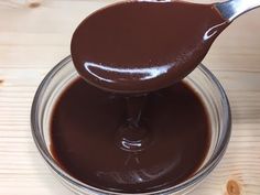 a spoon full of melted chocolate on top of a glass bowl