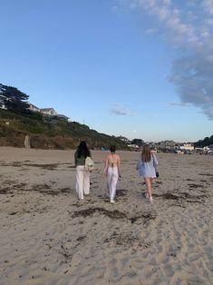 three women walking on the beach in bathing suits