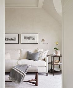 a living room with a white couch and two pictures on the wall next to it