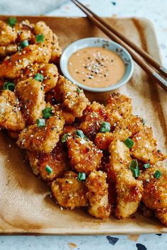 fried food with dipping sauce and chopsticks on a cutting board