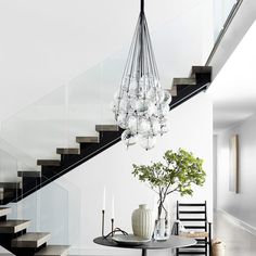 a dining room table with a vase on it and chandelier hanging from the ceiling