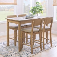 a dining room table with four chairs and a potted plant