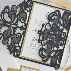 an ornate black and gold wedding card on a plate