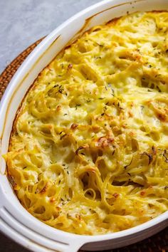 a casserole dish with cheese and herbs in it sitting on a wicker place mat