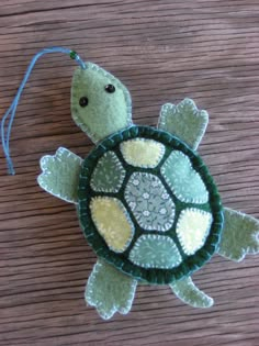 a stuffed turtle is sitting on a wooden surface with a string attached to it's back