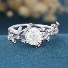 a diamond ring with leaves on the band and a center stone surrounded by small diamonds